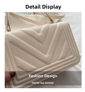 Detail shot of beige crossbody bag with V-shaped geometric texture and gold buckle