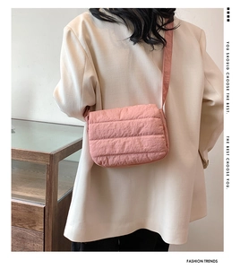 Rear view of a pink quilted crossbody bag styled with a cream blazer in a modern setting