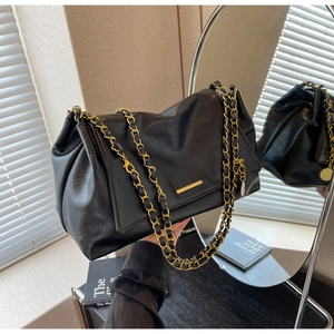 Close-up of black leather tote bag featuring gold hardware and leather woven chain strap