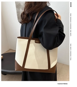 Detailed side view of a large cream and brown patchwork tote bag on a model shoulder