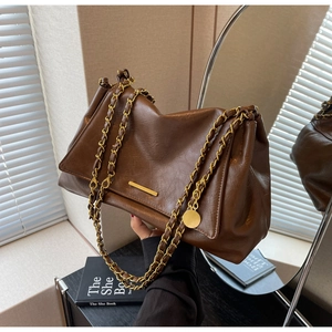 Detailed view of the dark brown leather tote bag with glossy finish and gold chain strap
