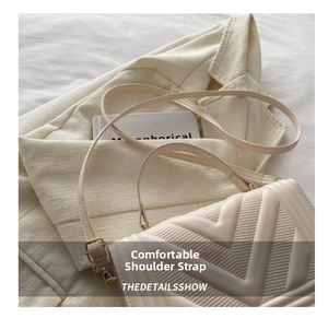Detail of cream leather bag with V-shaped quilting and gold hardware on beige suit