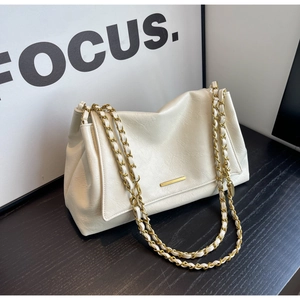 Close-up of cream faux leather shoulder bag with gold chain strap and metal hardware