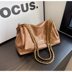 Detail of caramel leather shoulder bag with gold chain strap and metallic buckle