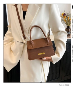 Detail view of brown lychee grain leather handbag with gold hardware and fashion lettering