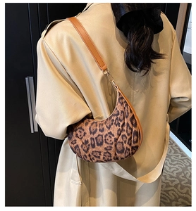 Close-up of leopard print crescent bag with leather trim and gold metal hardware