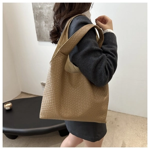 Side view of a large khaki woven tote bag on shoulder for vintage fall style