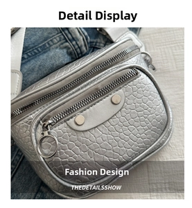 Detail view of silver embossed crossbody bag with metallic zipper and rivet accents