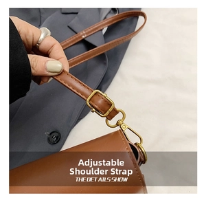 Detail of adjustable brown leather shoulder strap with elegant gold buckle and stitching