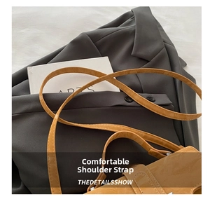 Detail of glossy brown leather shoulder bag with matching slim strap on grey blazer