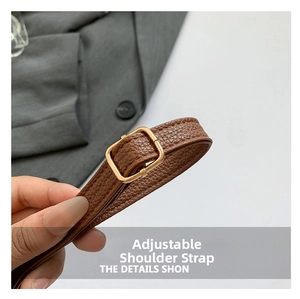 Detail of brown litchi pattern leather bag strap with adjustable gold buckle