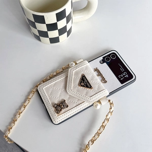 Detail of white leather Z Flip case with gold chain, pearl bear charms and lucky tag