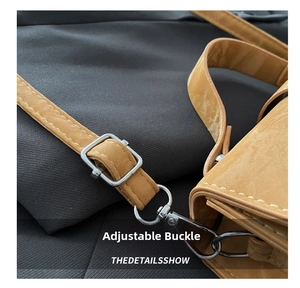 Detail of adjustable shoulder strap with metal buckle and stitching on tan handbag