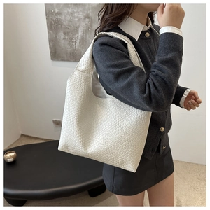 Detail of white woven leather tote bag shown on model with chic minimalist styling