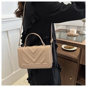 Chic beige crossbody bag featuring V-shaped quilting and decorative perforations