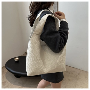 Detail of white woven tote bag with wide shoulder strap showing rich texture and capacity