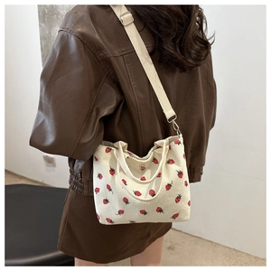 Detail of strawberry print corduroy bag shown worn as a crossbody by a model