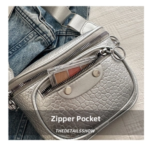 Close-up of silver textured crossbody bag featuring functional front zipper pocket details