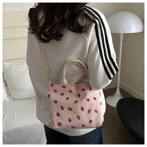 Detailed view of pink corduroy shoulder bag with strawberry print and adjustable strap