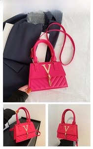 Detail of rose red handbag featuring gold V logo, tassel charm and V-shaped quilting