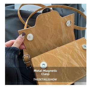 Detailed macro view of mustard yellow patent leather bag with double magnetic silver clasps