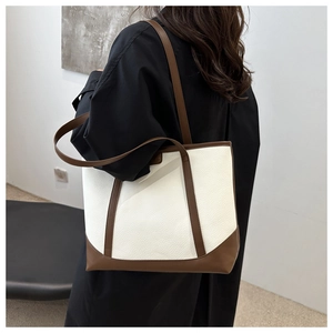 Detail of a large color-block tote bag with white lychee grain leather and brown trim