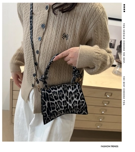 Detail of leopard print crossbody bag with curved base and knit cardigan outfit