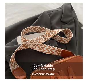 Detail of wide woven geometric strap with brown leather join and gold metal hardware