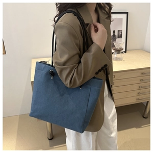 Détail du sac cabas en toile bleu foncé avec poignées en corde porté par un mannequin