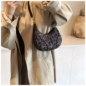 Detailed close-up of leopard print canvas fabric on a crescent shoulder bag with gold hardware