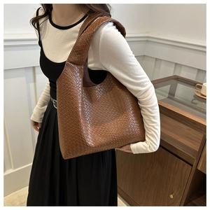 Macro detail of brown leather woven texture and artisan craftsmanship on a tote bag
