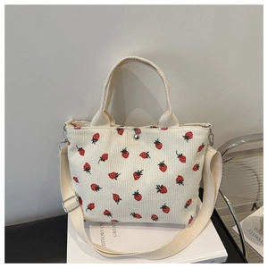 Detail of strawberry embroidery on cream corduroy tote bag with adjustable strap
