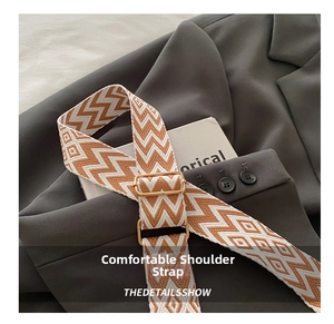 Detail of wide woven shoulder strap in orange and white with golden metal buckle