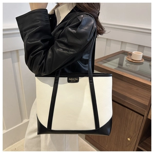 Detail of minimalist black and white tote bag showing leather texture and contrast stitching