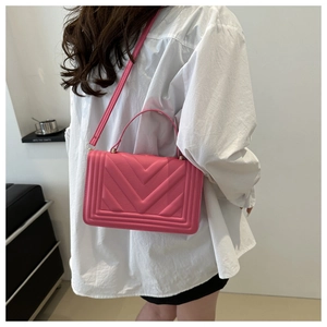 Detail of rose pink crossbody bag with V-shaped chevron quilting on high-quality synthetic leather