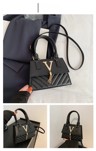 Macro detail of black quilted shoulder bag featuring gold V logo and tassel ornament
