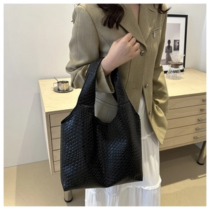 Detail of hand-woven black tote bag styled with casual minimalist autumn outfit