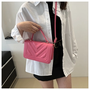 Detail of pink crossbody bag with V-shaped geometric texture and gold metal buckle