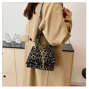 Dettaglio borsa leopardata con fibbia in metallo a V dorata e nappa decorativa