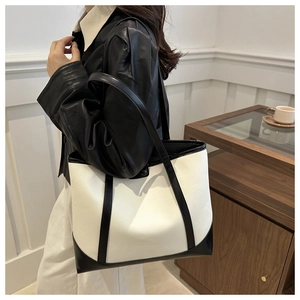 Detail of minimalist black and white tote bag showing lychee grain leather texture