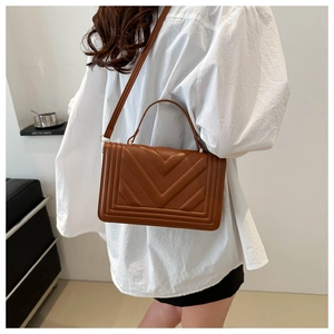 Close-up of brown leather crossbody bag with V-shaped embossed patterns and strap