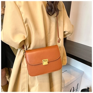 Detail of caramel leather crossbody bag with golden metal buckle and stitching