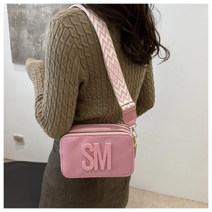 Detail of pink camera bag with 3D SM logo and geometric pattern wide shoulder strap