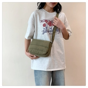 Detail of army green quilted crossbody bag with adjustable wide strap shown on model