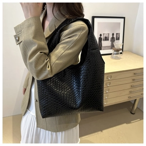 Detail view of large black woven texture hobo shoulder bag worn on a model