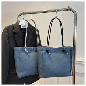 Detail of denim tote bags with knotted rope handles in minimalist casual style