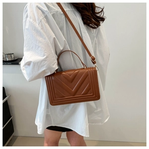 Detail of V-quilted brown PU leather crossbody bag featuring top handle and slim strap