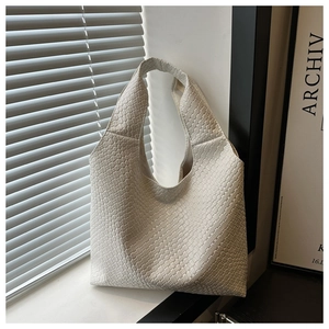 Detailed close-up of woven texture on minimalist cream hobo bag in soft natural light