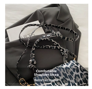 Close-up of leopard print shoulder strap with adjustable gold buckle on fabric bag