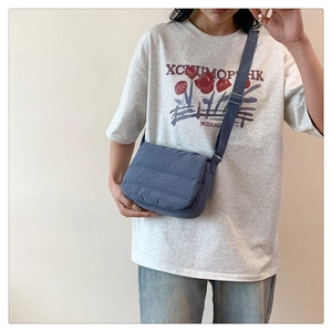Detail of dark blue quilted crossbody bag with horizontal stitching and adjustable strap